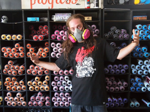 Owner Chase Jensen demonstrates the variety of graffiti paints his store sells.